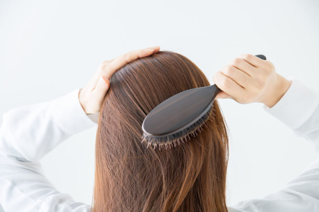 「ヘアブラシで髪を整える女性」のイメージ画像